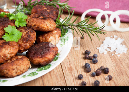 In casa le polpette di carne su un piatto servito con vari ingredienti su di un tavolo di legno Foto Stock