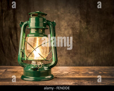 Vintage olio lampada accesa sul tavolo di legno su sfondo scuro Foto Stock