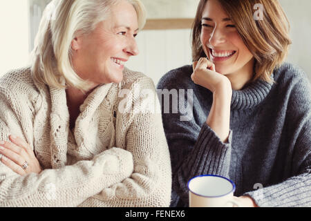 Ridere la madre e la figlia in maglioni di bere il caffè Foto Stock