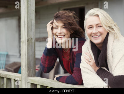 Ritratto sorridente madre e figlia sul portico ventoso Foto Stock