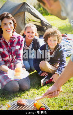 Famiglia guardare padre cottura alla brace al campeggio grill Foto Stock