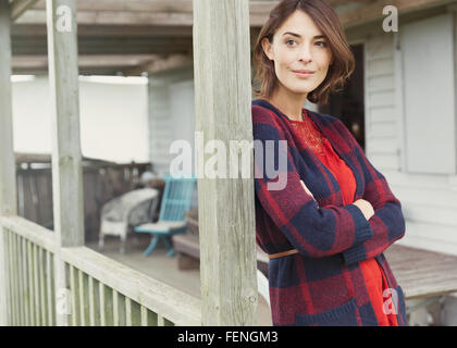 Malinconici donna in maglione che guarda lontano sul portico Foto Stock