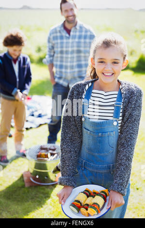 Ritratto sorridente ragazza con gli spiedini di vegetali a sunny campeggio Foto Stock