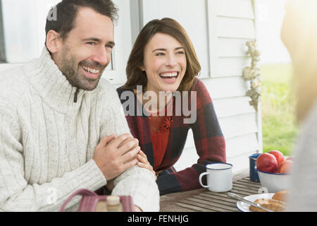 Coppia sorridente parlando a tavola sul patio Foto Stock