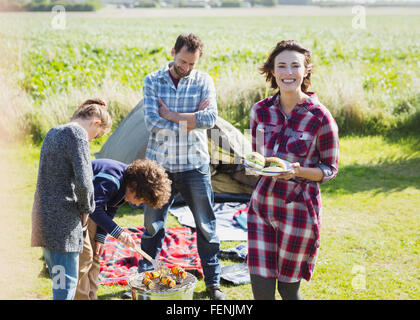 Ritratto di famiglia sorridente alla brace a sunny campeggio Foto Stock