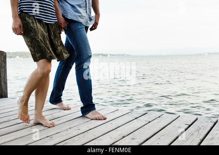 Vista ritagliata della coppia romantica passeggiando sul molo in legno, il lago di Starnberg, Baviera, Germania Foto Stock