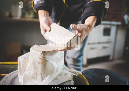 Vista ritagliata della metà adulto mans mani rimozione blocco di argilla dal sacchetto di plastica Foto Stock