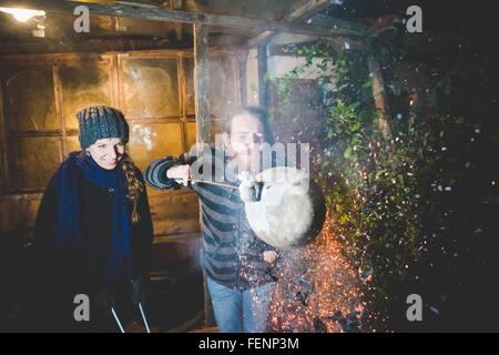 Giovane Azienda hot pot di argilla in pinze, soffiaggio, causando la formazione di scintille Foto Stock