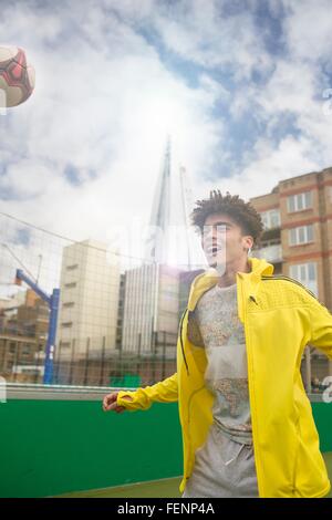 Giovane uomo che giocano a calcio su urban football pitch Foto Stock