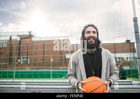 Ritratto di metà uomo adulto tenendo la pallacanestro Foto Stock