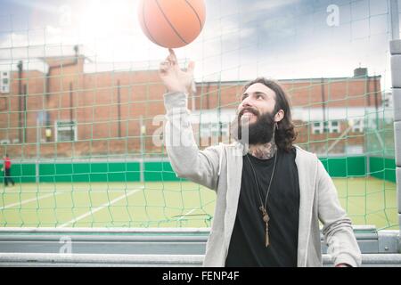 Metà uomo adulto la filatura la pallacanestro sul dito Foto Stock