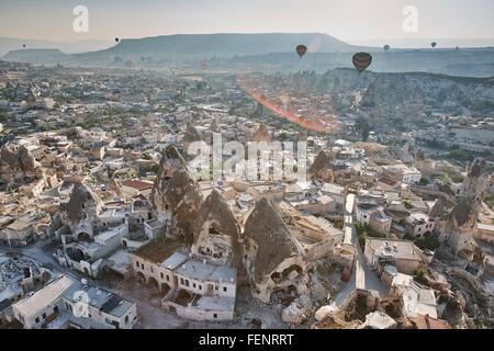 Vista in elevazione delle mongolfiere su formazioni rocciose e abitazioni, Cappadocia, Anatolia,Turchia Foto Stock