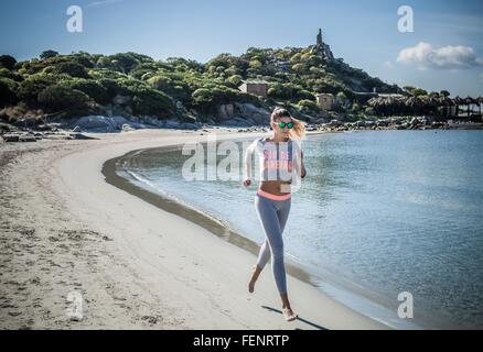 Femminile in esecuzione lungo la spiaggia, a Villasimius, Sardegna, Italia Foto Stock