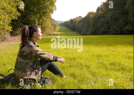 Giovane donna seduta nel campo guardando il paesaggio, Great missenden, Buckinghamshire, R.U. Foto Stock