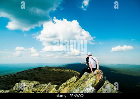 Giovane maschio escursionista seduta su roccia affacciato sul paesaggio, Russia Foto Stock