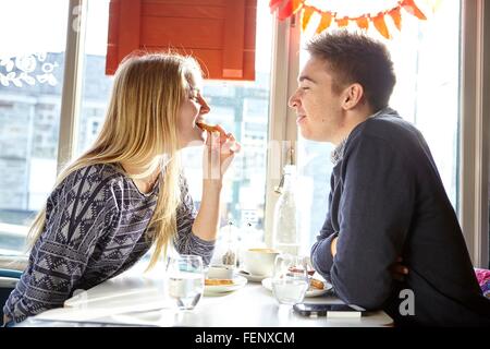Romantico coppia giovane mangiato in cafe sedile finestra Foto Stock