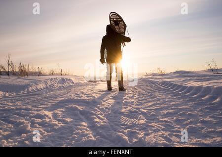 Vista posteriore del profilarsi l uomo che trasportano le racchette da neve sulle spalle nel paesaggio innevato, Ural, Russia Foto Stock