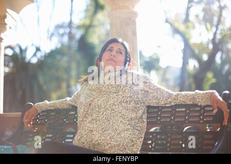 Donna matura, seduto al banco delle cuffie da indossare che guarda lontano, Siviglia, Spagna Foto Stock