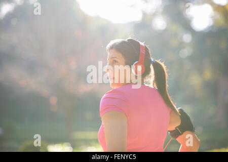 Vista posteriore della donna matura che indossano le cuffie e fascia da braccio che guarda lontano Foto Stock