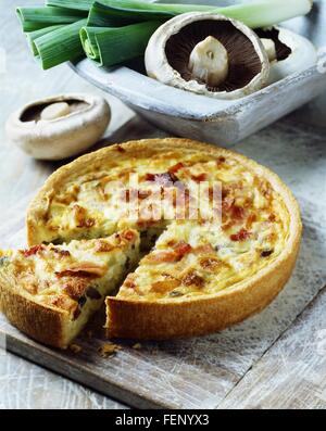 Prosciutto, funghi e porri quiche su bianco lavato tagliere Foto Stock