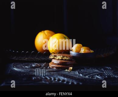 Lusso ricoperti di cioccolato al gusto di arancia biscotti e arance sul tavolo vintage, chiave di basso Foto Stock