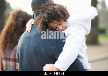 Vista posteriore del padre che porta la figlia del sonno Foto Stock