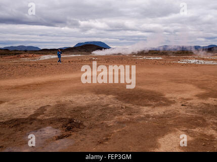 A nord-est dell'Islanda, dell'Islanda. 1 agosto, 2015. Una passeggiate turistiche passato il vapore caldo e pennacchi di fumo salendo attraverso il terreno vulcanico del Namaskard-Namafjall-Hverir Campi geotermici dalle sue acque sulfuree piscine di fango bollente e vapore molle. Nel nord-est dell'Islanda, sul lato est del Lago Myvatn, il turismo è diventato un settore in crescita dell'economia e l'Islanda è diventata una destinazione turistica preferita. © Arnold Drapkin/ZUMA filo/Alamy Live News Foto Stock