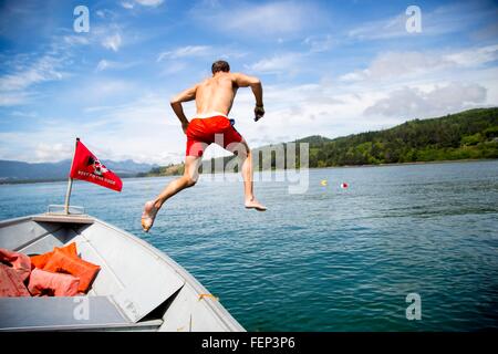 Metà uomo adulto il salto in mare dalla barca, Nehalem Bay, Oregon, Stati Uniti d'America Foto Stock