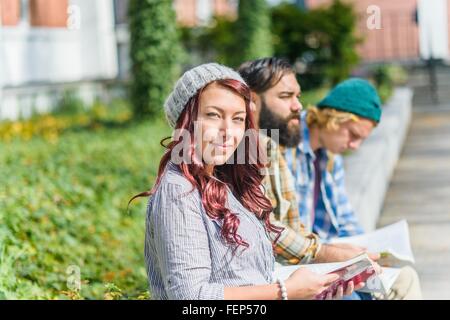 Ritratto di adulto studenti universitari la lettura di libri sulla parete del campus Foto Stock