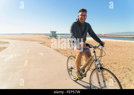 Giovane uomo escursioni in bicicletta lungo il percorso a beach Foto Stock