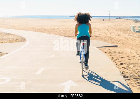 Metà donna adulta escursioni in bicicletta sul sentiero in spiaggia, vista posteriore Foto Stock