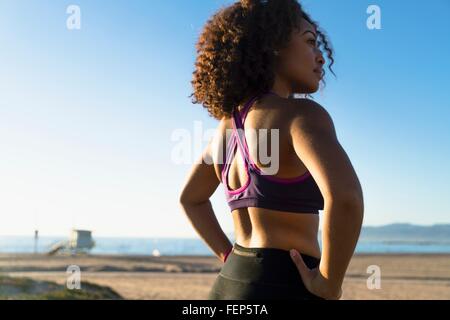 Metà donna adulta, mani sui fianchi, vista posteriore Foto Stock