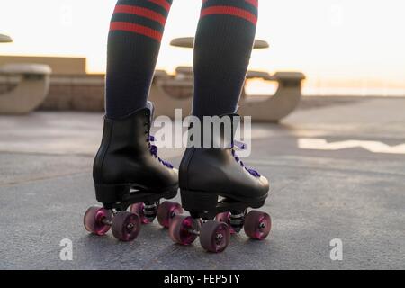 Metà donna adulta su rollerskates, vista posteriore, sezione bassa Foto Stock