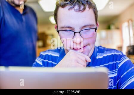 Giovane uomo con la sindrome di down, tenendo corsi di informatica classe Foto Stock