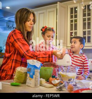 Madre e bambini in cucina, con frusta a mano Foto Stock