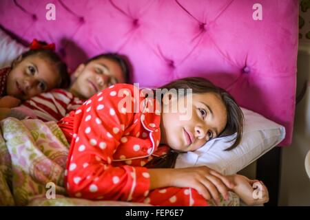 Ragazzo e due sorelle che giace nel letto prima di andare a dormire Foto Stock