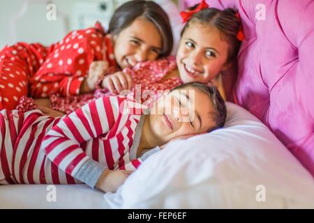 Ragazzo simpatico e due sorelle che giace nel letto sogghignando Foto Stock