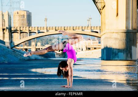 Vista laterale della danzatrice facendo handstand, gambe aperte, Los Angeles, California, Stati Uniti d'America Foto Stock