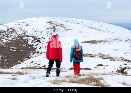 Due uomini sono alta a piedi nella neve in montagna durante l'inverno. Foto Stock