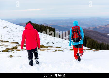Due uomini sono alta a piedi nella neve in montagna durante l'inverno. Foto Stock