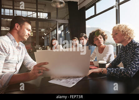 Felice e vincente squadra di colleghi seduti insieme per elaborare i piani aziendali Foto Stock