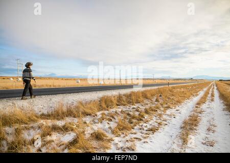 Donna che cammina lungo la strada di campagna, Islanda Foto Stock
