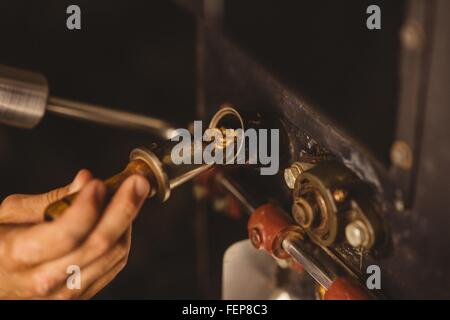 L'uomo versando i chicchi di caffè in caffè tostatore, close-up Foto Stock