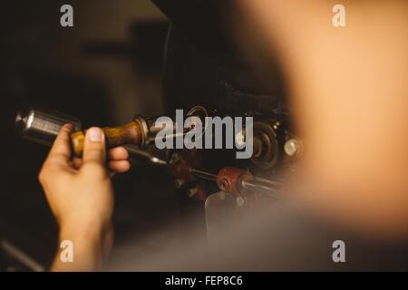 L'uomo versando i chicchi di caffè in caffè tostatore, vista posteriore Foto Stock