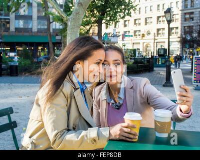 Giovane femmina adulta gemelli tenendo selfie nel parco della città Foto Stock