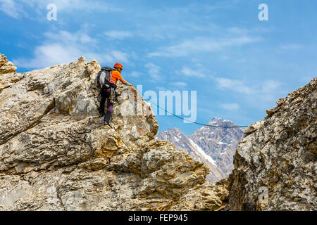 Uomo coraggioso si arrampica rocky ridge Foto Stock