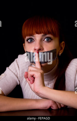 Ragazza con la bocca sigillata con nastro portato dito per la sua bocca silenziosa di chiamata Foto Stock