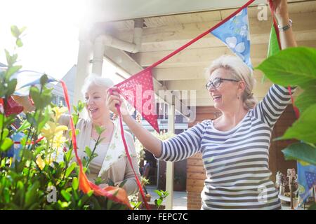 Due donne in giardino, colorati appesi bunting Foto Stock