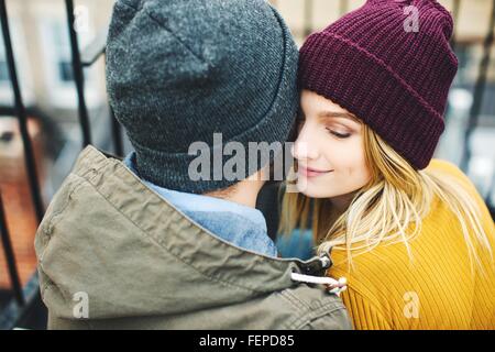 Romantico coppia giovane indossando cappelli a maglia seduta sulla scaletta Foto Stock