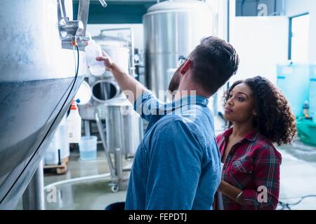 I colleghi nella fabbrica di birra a discutere di serbatoio di fermentazione Foto Stock